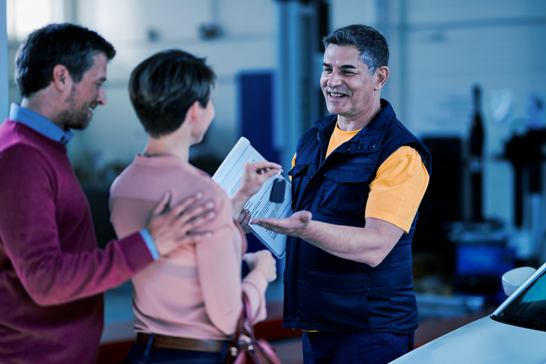 Cliente entregando a chave do carro para o mecânico no pátio da oficina,