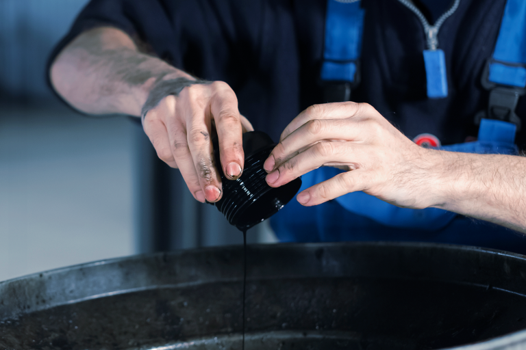 Pessoa despejando óleo de carro em um recepiente.
